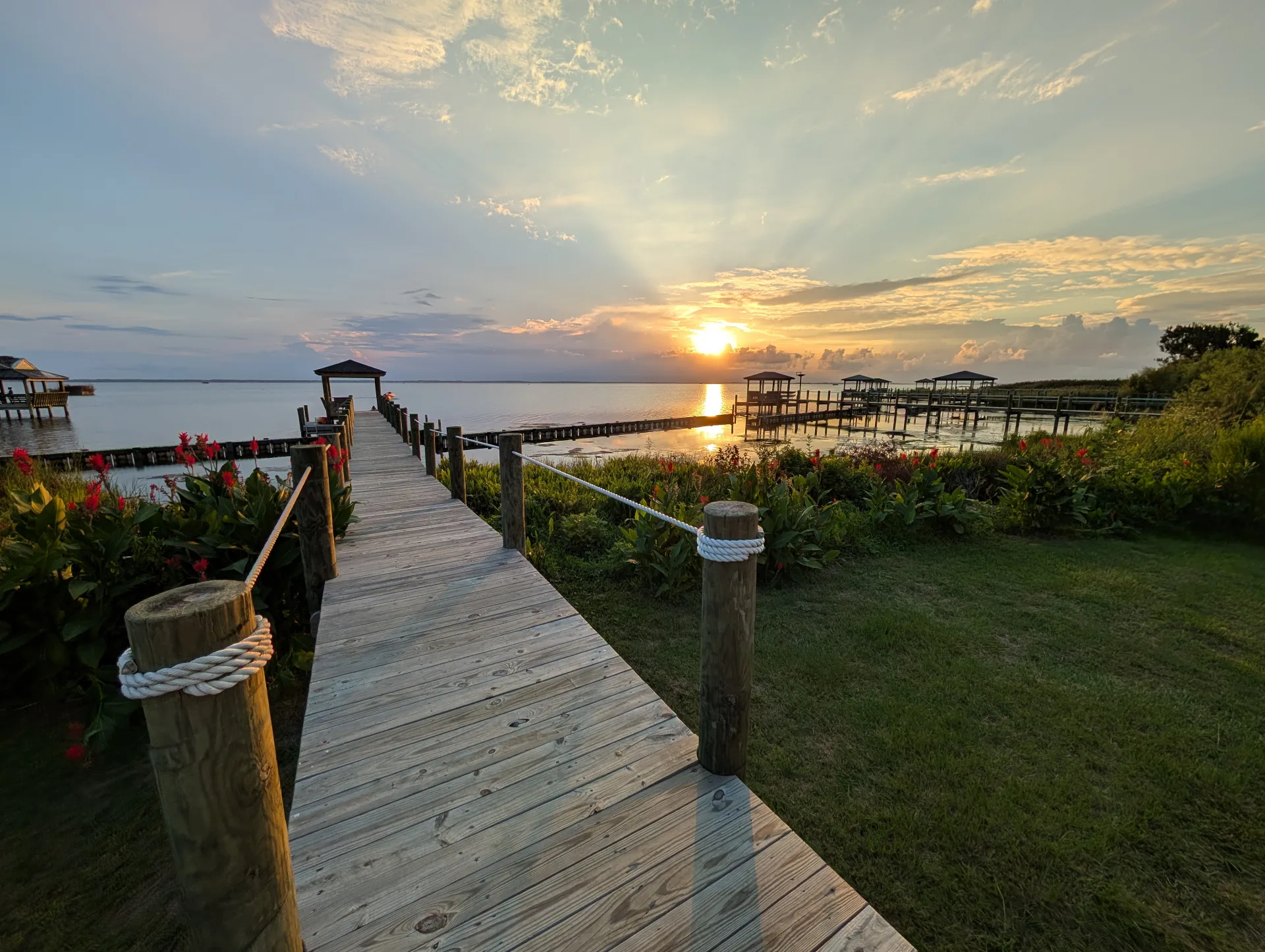 Wooden dock walkway with rope railings leading to Currituck Sound at sunset at Hygge on the Bay